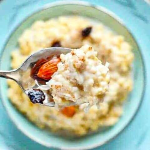 a spoon of millet porridge with almonds and raisins on a spoon.