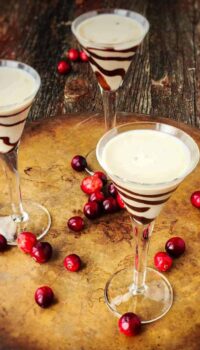 homemade Bailey Irish cream in tall stemmed glasses with chocolate drizzled in the glass.