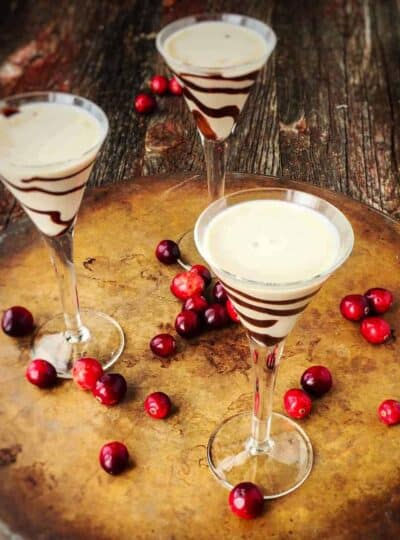 homemade Bailey Irish cream in tall stemmed glasses with chocolate drizzled in the glass.