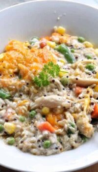 Turkey rice casserole with mixed vegetables shown in a white bowl with a spoon.