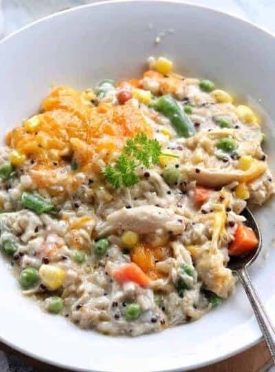 Turkey rice casserole with mixed vegetables shown in a white bowl with a spoon.