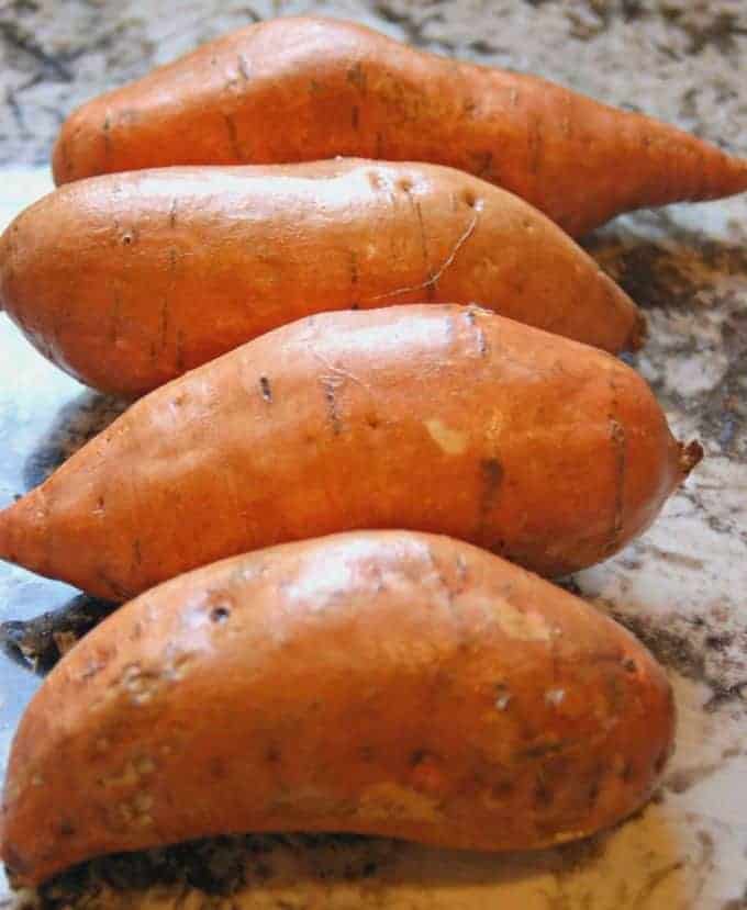 4 sweet potatoes shown on a counter.