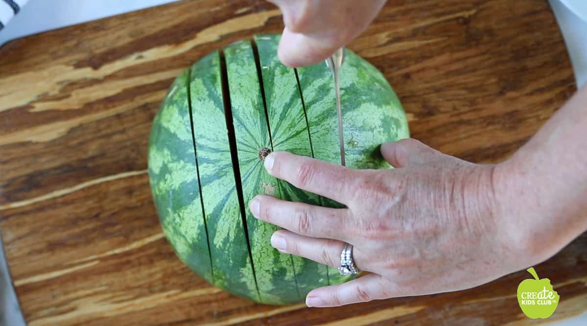 Half of a watermelon is being sliced horizontally.