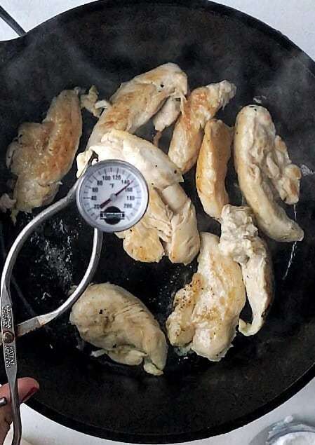 Chicken tenders in a skillet with a thermometer.