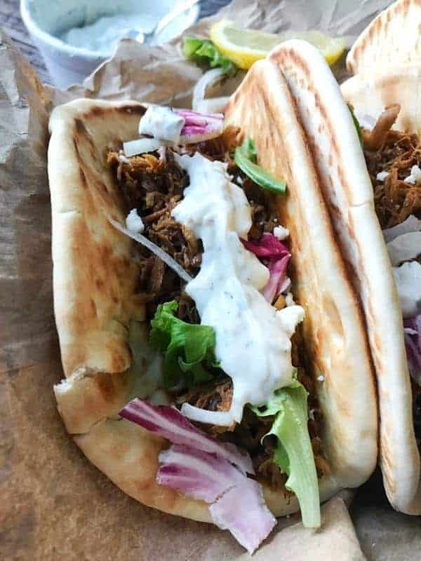 a pita with pulled pork topped with sauce and veggies.