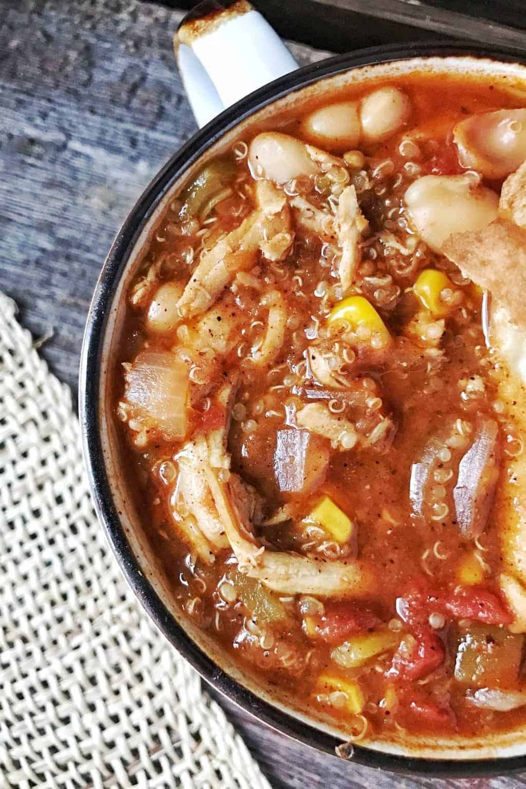 A top down picture showing tortilla coup in a mug with chicken, corn, and quinoa.