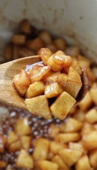 Sautéed diced apples caramelized in a baking pan with wooden spoon.