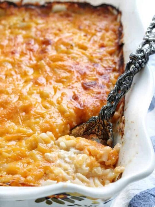 cheesy potatoes in a baking pan with a spoon