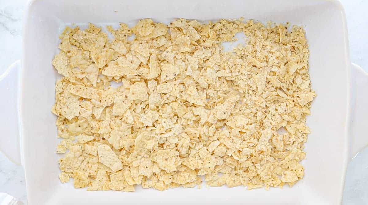  crushed tortilla chips in the bottom of a baking dish
