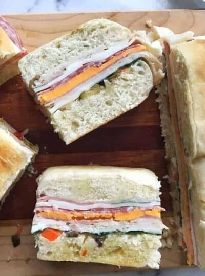 A sandwich cut in half on a plate, with Muffuletta