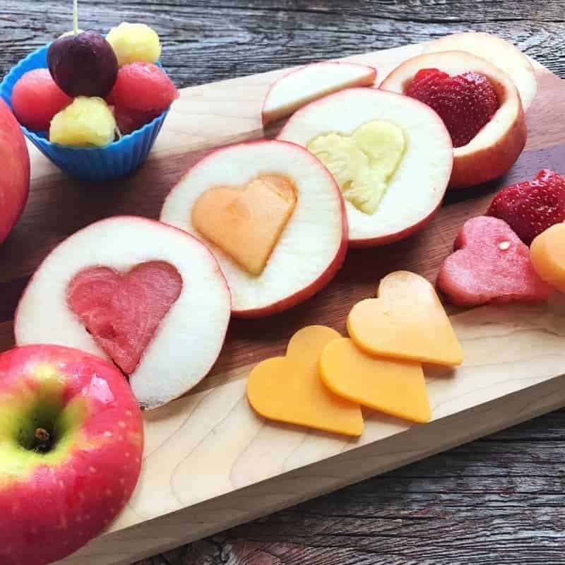 A bowl of fruit on a cutting board