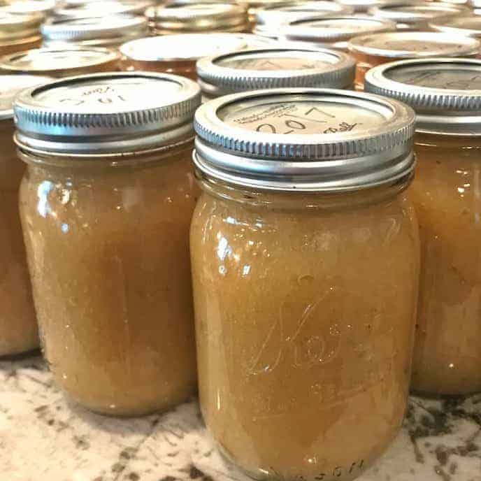 jars of applesauce shown on a counter after canned. The tops are labeled with the year. 