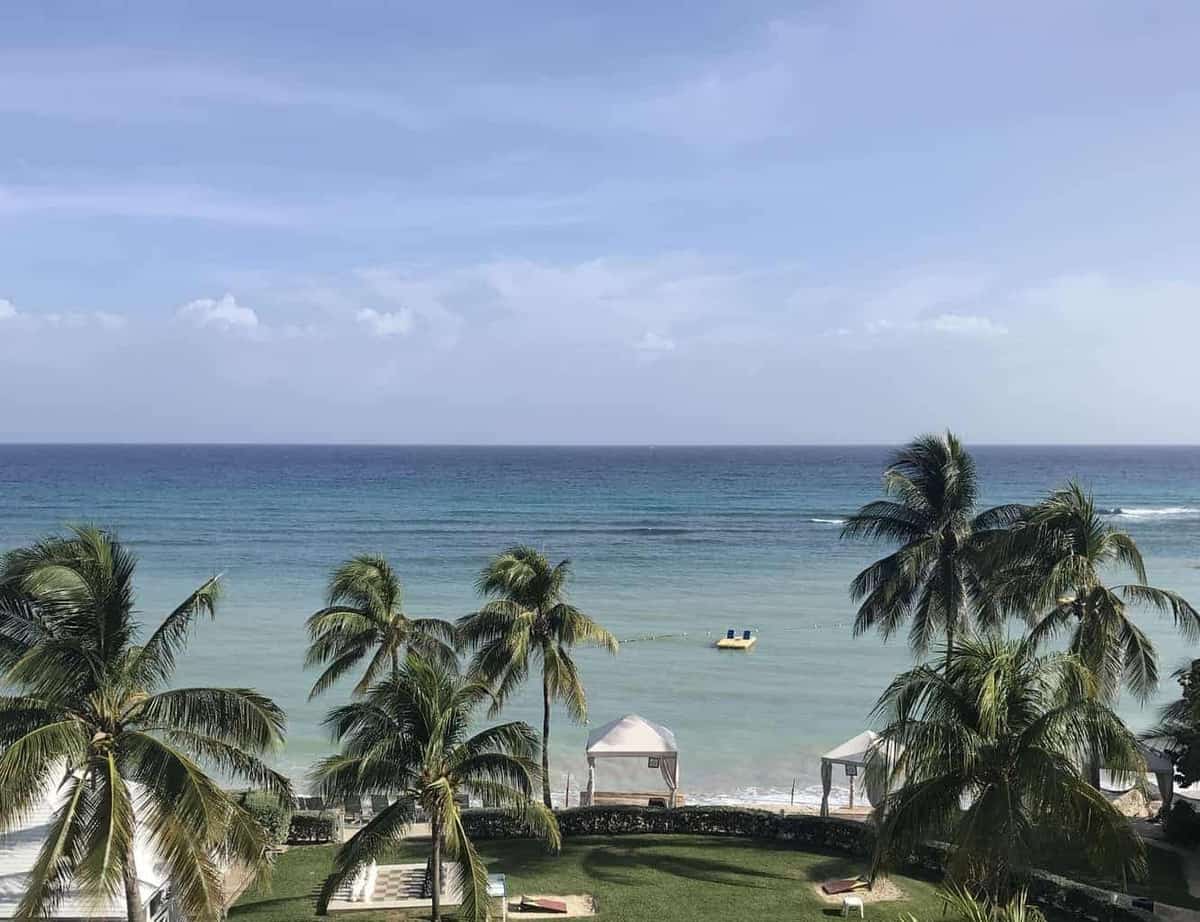 The view from an ocean front room at Hilton Rose Hall Jamaica, showing the ocean and palm trees overlooking some large outdoor board games