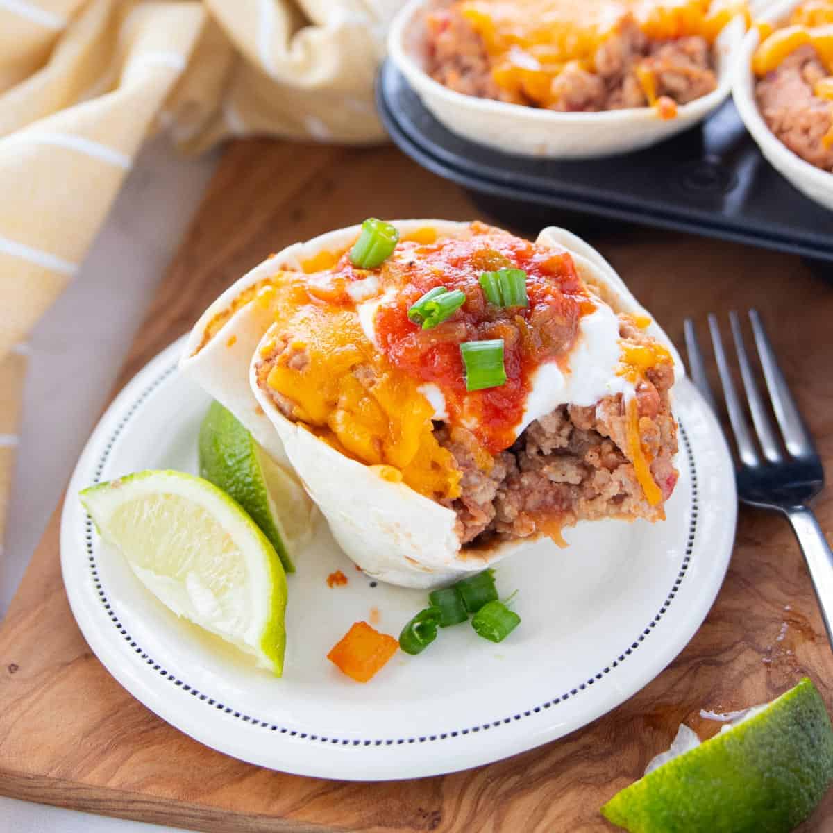 a taco cup on a plate with lime slices next to the taco cup