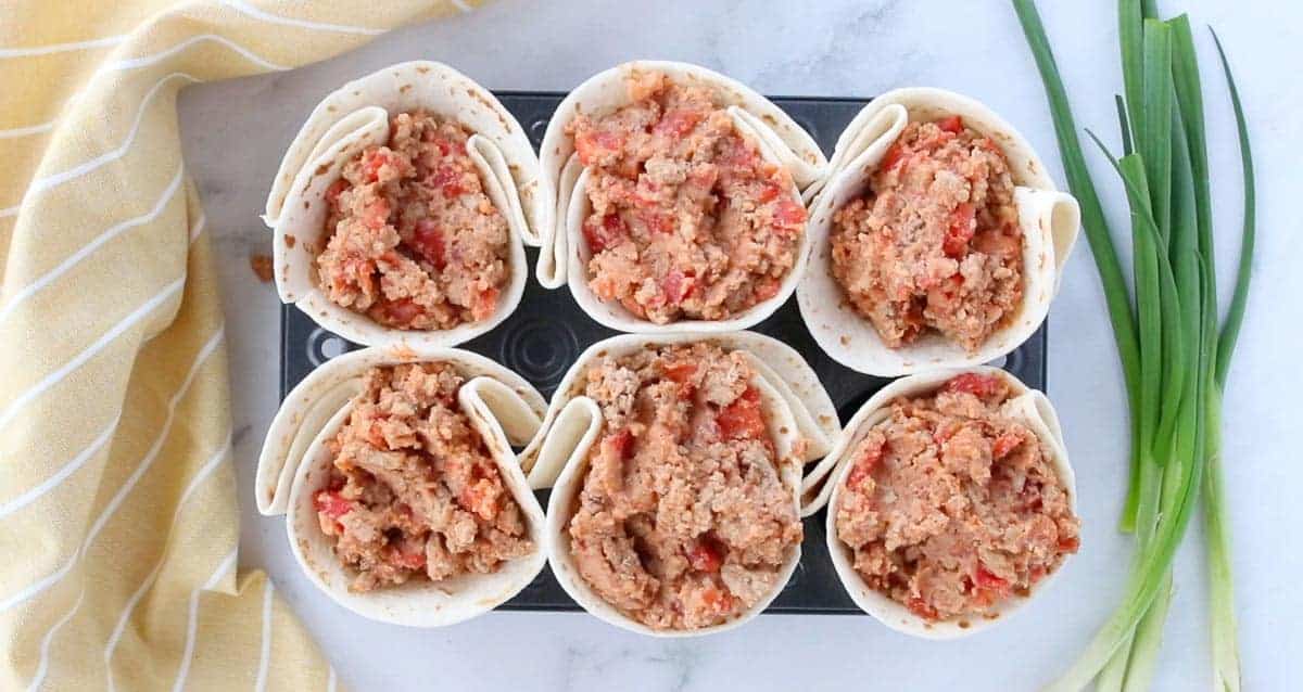 Baked Taco Cups being filled with the ground beef mixture before being placed in the oven.