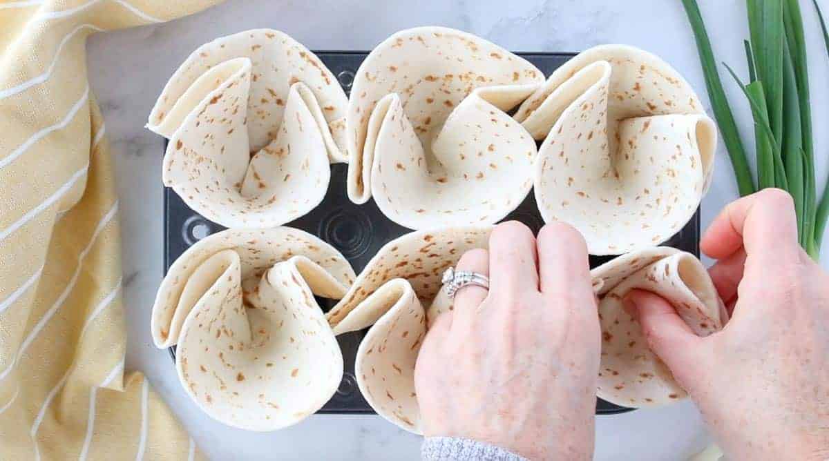 Taco Cups being folded into a cup shape before being placed in the oven.
