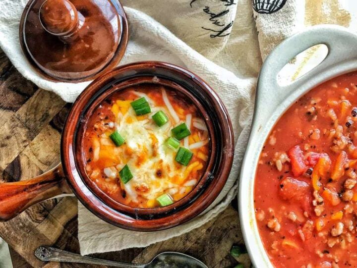 A bowl of Soup with peppers and cheese