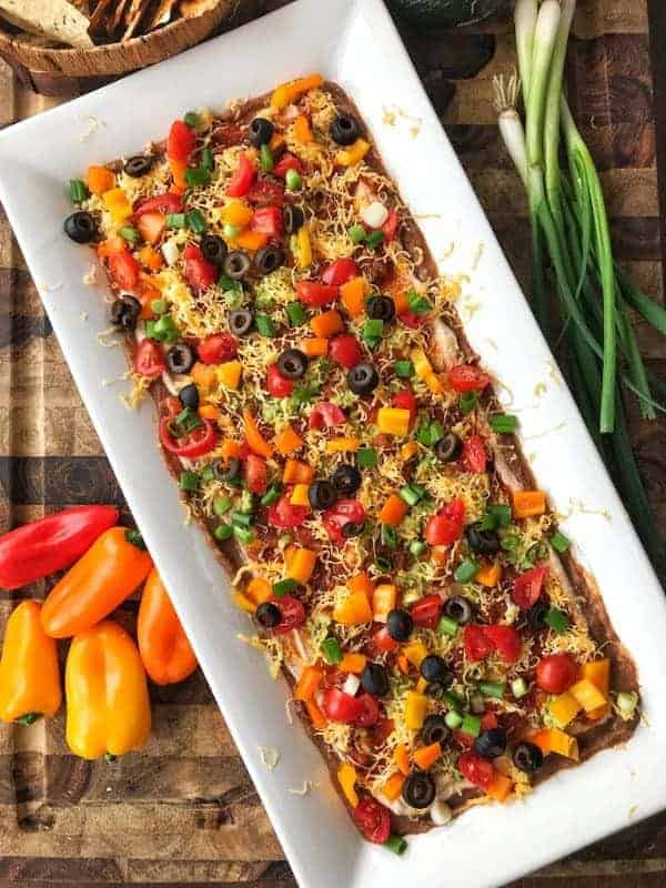 Refried bean dip recipe shown finished on a white serving tray.