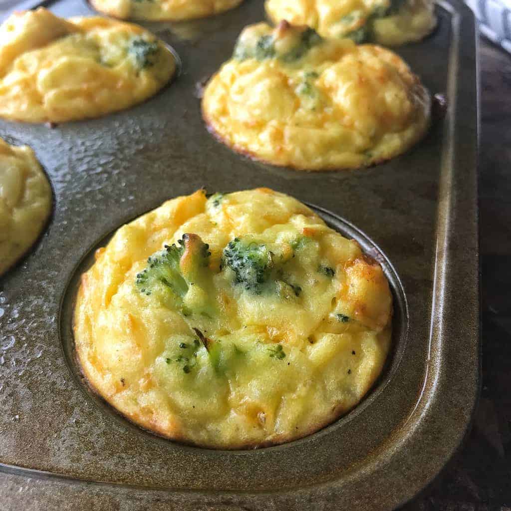 Mashed potato bites show in a muffin tin with cheese and broccoli cooked in. 