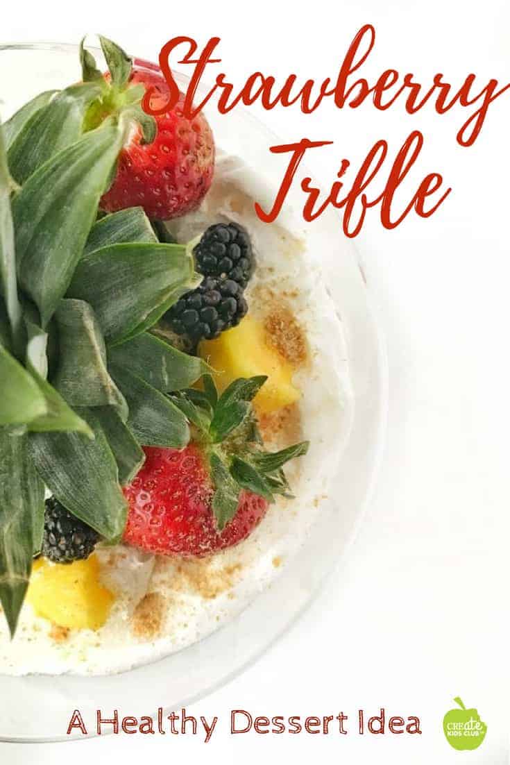 strawberry lemon trifle dessert shown from above in a clear bowl with fresh fruit and a pineapple stem on a white background