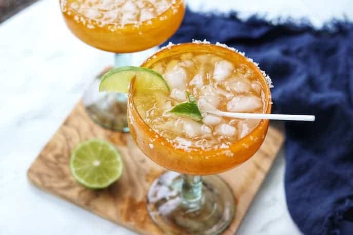 A glass of margaritas with lime and ice.