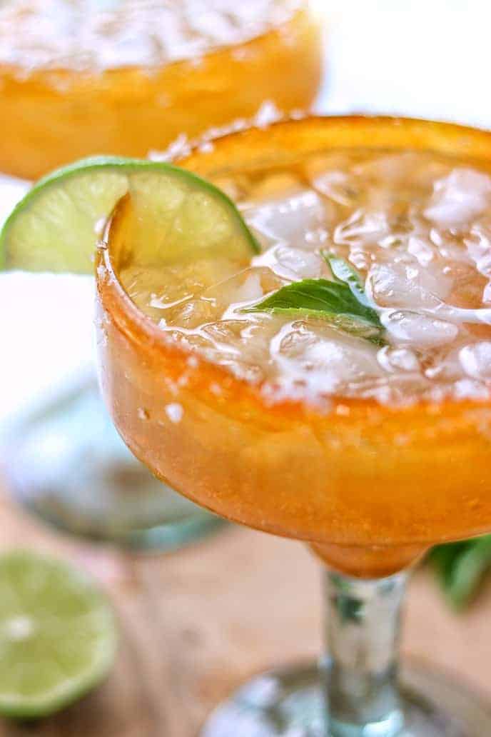 A glass of margaritas with lime and ice.