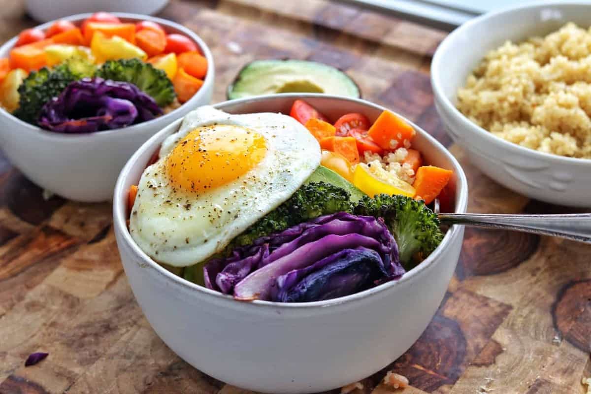 a buddha bowl with vegetables and a fried egg.