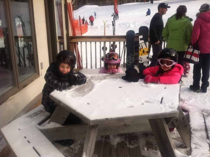 A group of kids sitting at a table at a ski hill