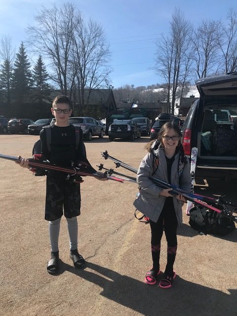 kids holding skis in a parking lot