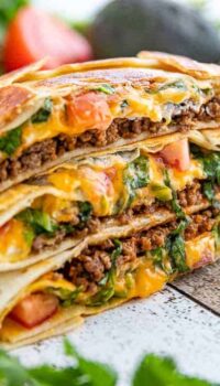 three stacked Crunchwrap supremes with beef and cheese oozing out.