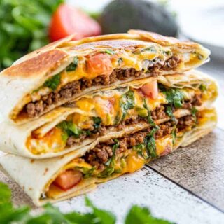 three stacked Crunchwrap supremes with beef and cheese oozing out.