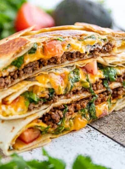 three stacked Crunchwrap supremes with beef and cheese oozing out.