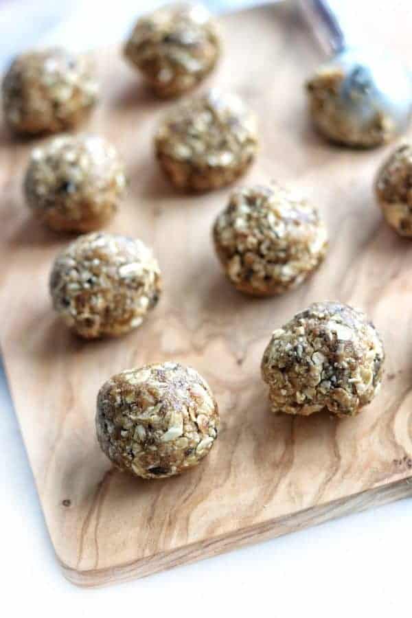 8 peanut butter energy balls on a wooden tray on a white surface.