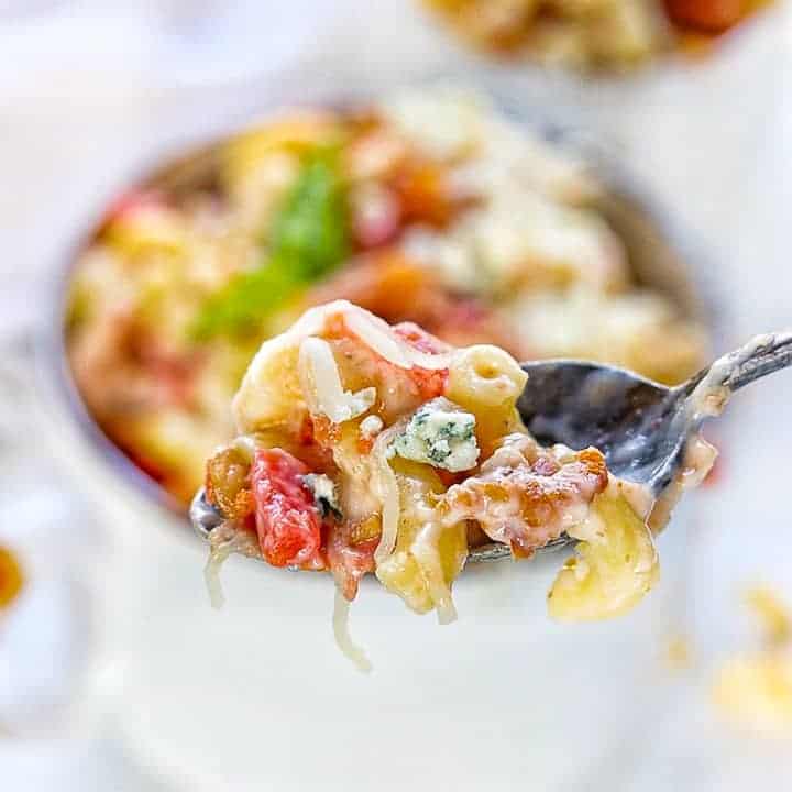 blue cheese mac and cheese with bacon shown up close on a spoon with the bowl of pasta in the background blurred.