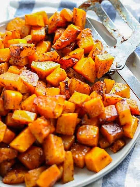 roasted butternut squash brown sugar shown on a white plate cut into cubes.