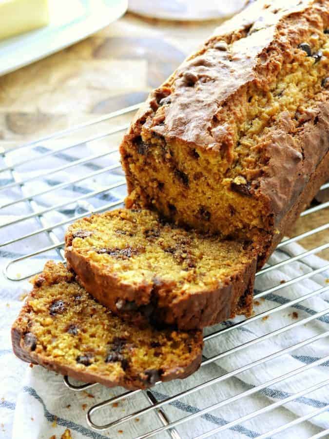 Chocolate chip pumpkin bread recipe just like great harvest pumpkin bread shown sliced packed with chocolate chips on a wire rack.