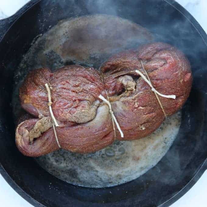 Beef Tenderloin Steak is in a black cast iron pan with the first side being seared.