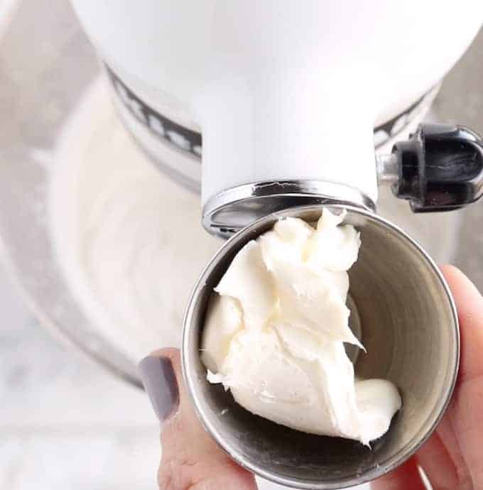  Crème à fouetter stabilisée en cours de fabrication, montrant le fromage à la crème dans un petit bol en métal devant un mélangeur blanc.