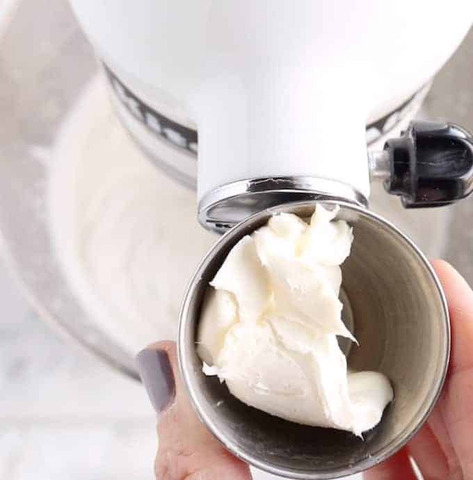 Crème à fouetter stabilisée en cours de fabrication, montrant le fromage à la crème dans un petit bol en métal devant un mélangeur blanc.