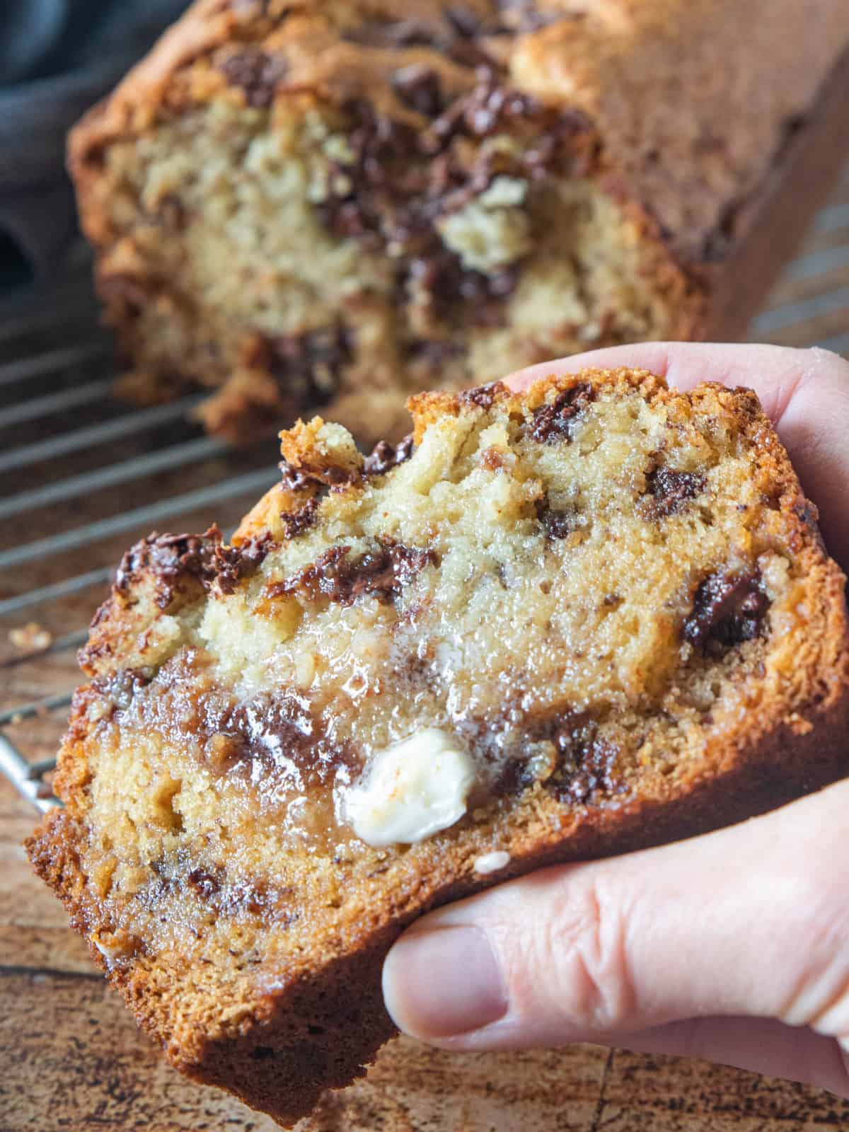 A close up of a slice of banana bread with melted butter and melted chocolate chips. 