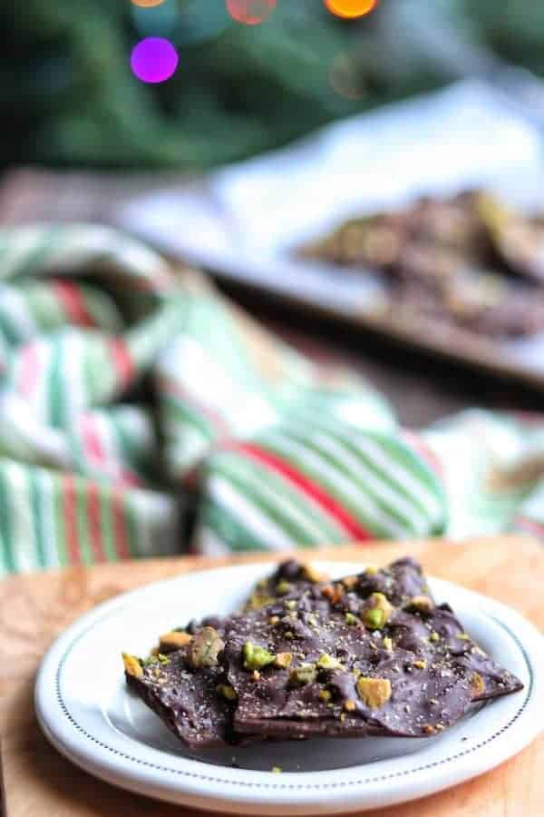  Chocolate bark on a white plate with a red and green towel in the background.