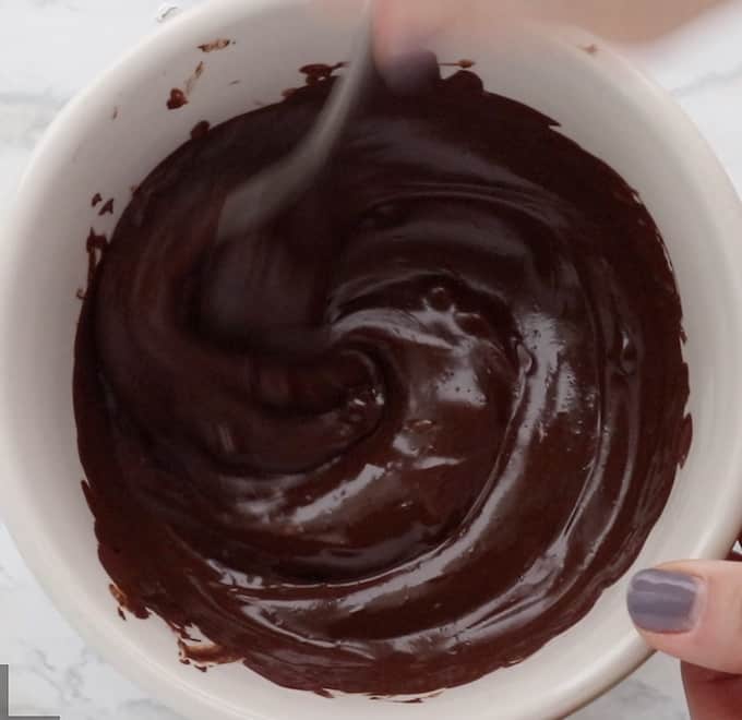 Melted chocolate chips in a white glass bowl.