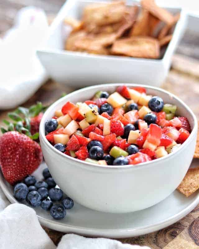 Fruit salsa in a serving bowl with pita chips next to the bowl.