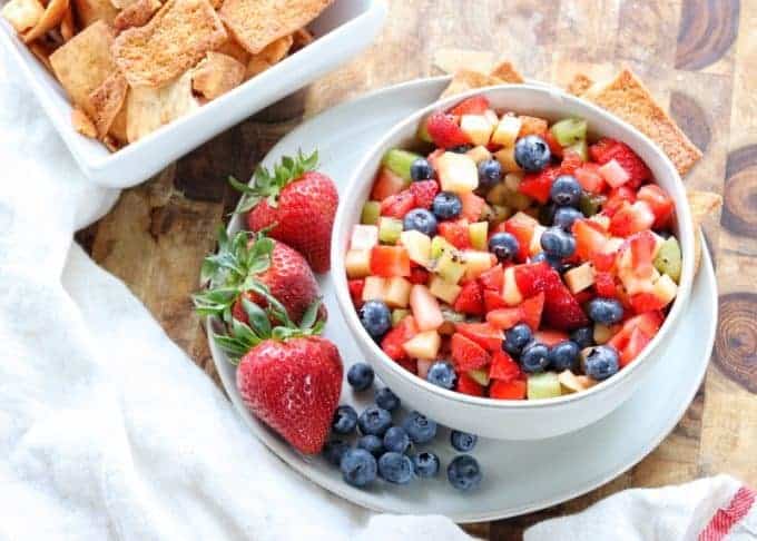 Fruit salsa in a serving bowl next to a bowl of cinnamon and sugar pita chips.