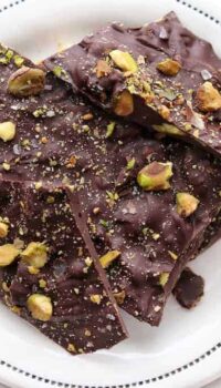 Dark chocolate pistachio bark shown on a white plate.