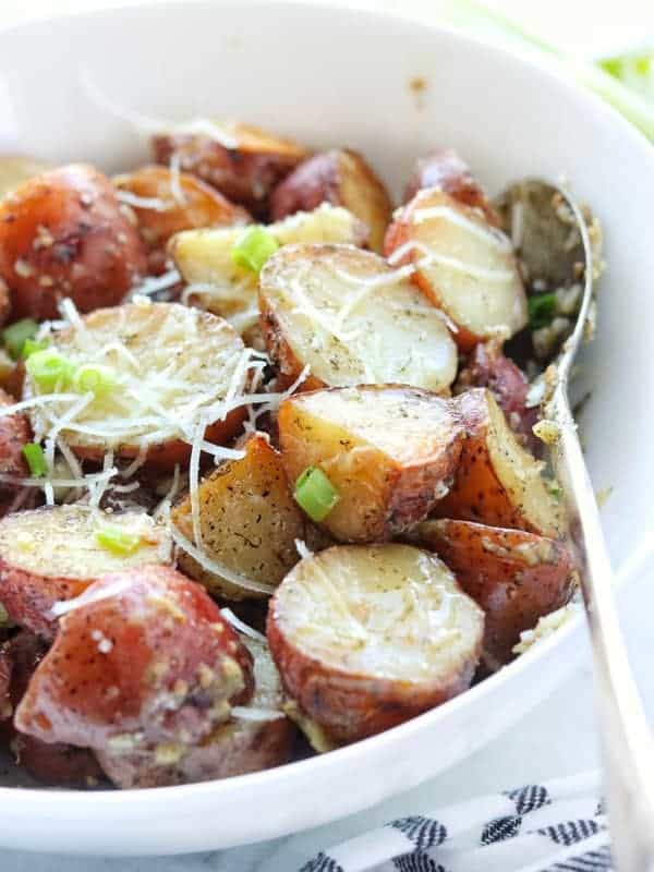 crock pot red potatoes shown up close in a white bowl with silver spoon. 