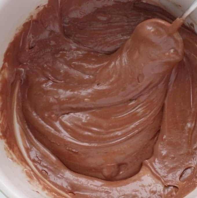 Melted chocolate being stirred in a white bowl. 