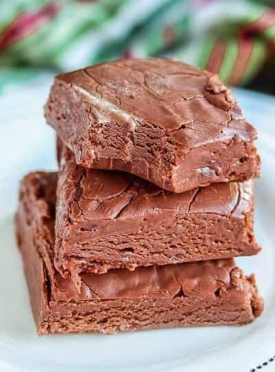 Three pieces of fudge stacked on top of each other, the top piece with a bite out of it.