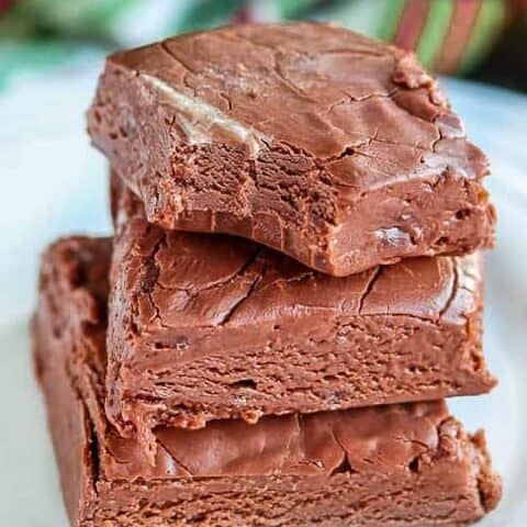Three pieces of fudge stacked on top of each other, the top piece with a bite out of it.
