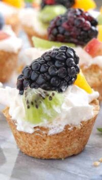 Mini Tarts a mini fruit tart recipe shown on white marble with a fresh blackberry on top with kiwi and peach.